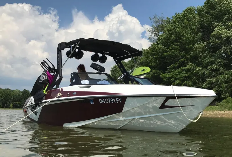 Slide: The Image of 2018 Axis T 22 boat on water, surrounded by trees and clear sky. - 1