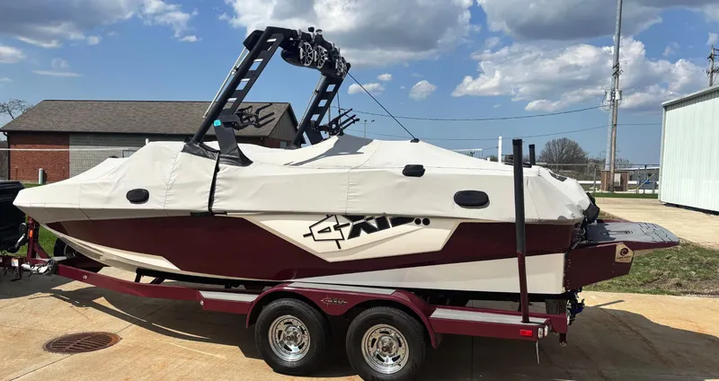 Slide: The Image of 2018 Axis T 22 boat on trailer, covered, parked outdoors under cloudy sky. - 2