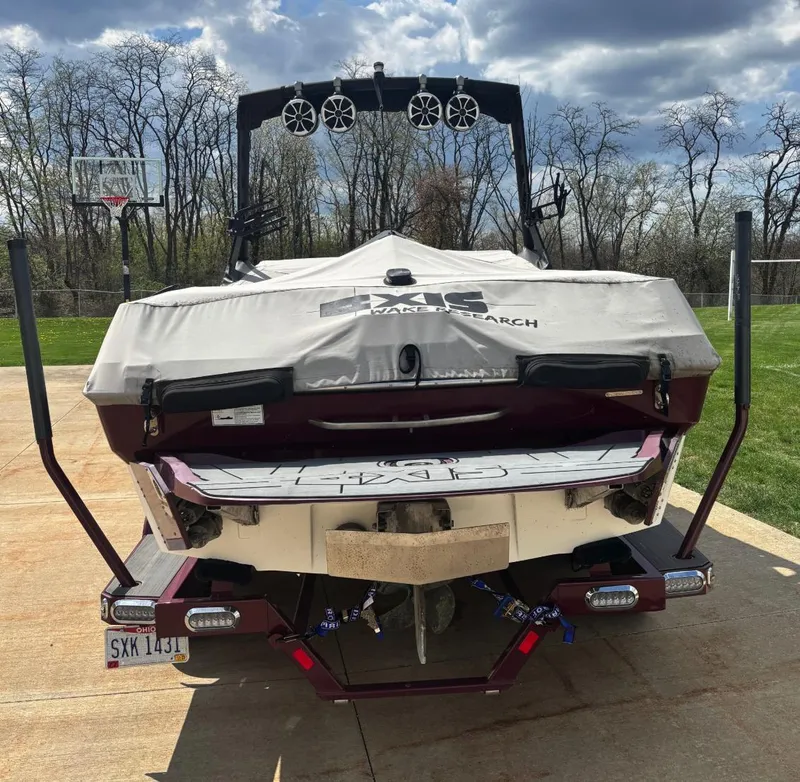 Slide: The Image of 2018 Axis T 22 boat with cover, parked on driveway, trees in background. - 3