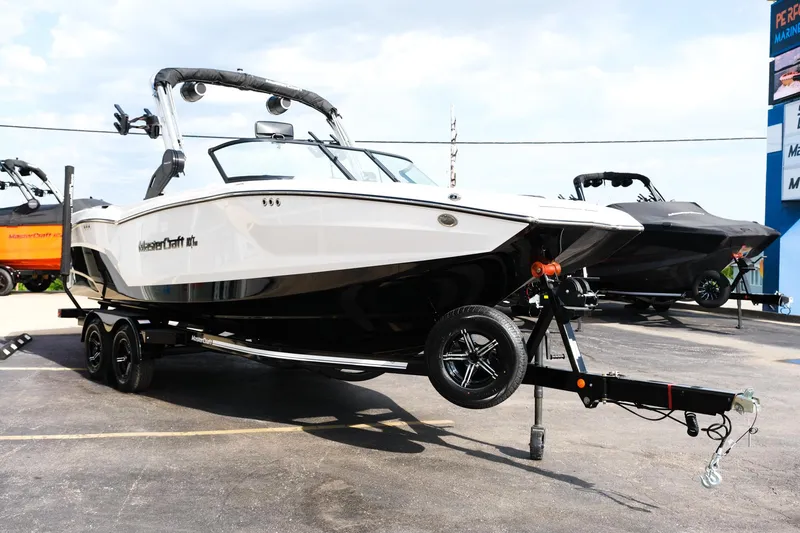 Slide: The Image of 2025 MasterCraft NXT24 boat on trailer, parked outdoors. - 11