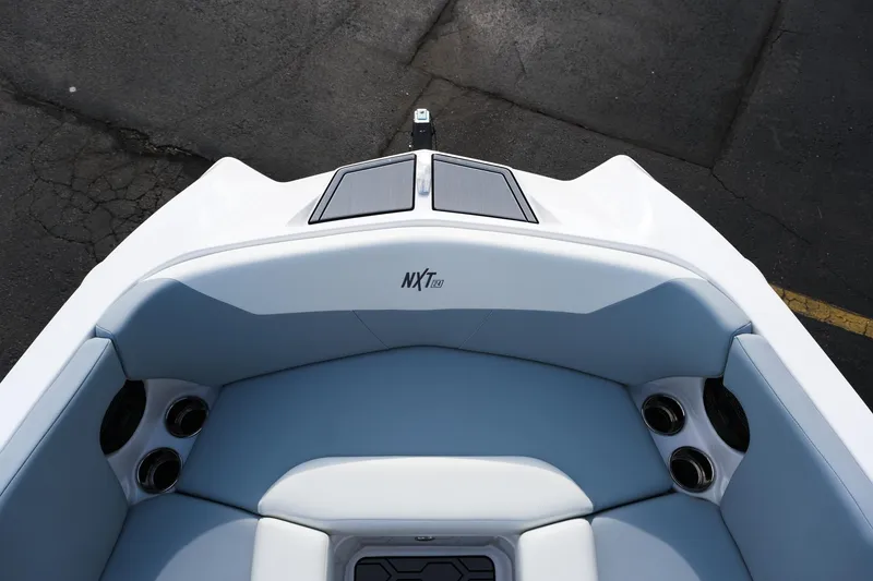 Slide: The Image of 2025 MasterCraft NXT24 boat interior with cushioned seating and cup holders. - 37