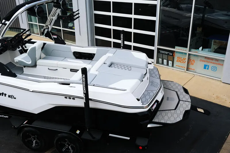 Slide: The Image of 2025 MasterCraft NXT24 boat on trailer, sleek design, parked outside showroom. - 6