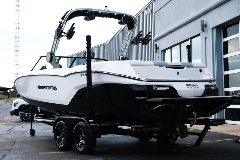 Slide: The Image of 2025 MasterCraft NXT24 boat on trailer, parked outside a building. - 7