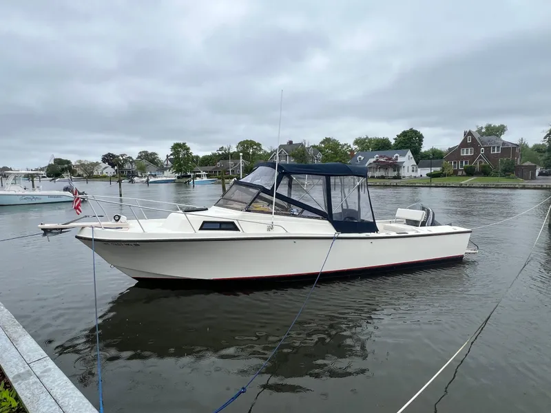 Slide: The Image of 1989 Mako 250 Cuddy Cabin boat docked on a calm river. - 4