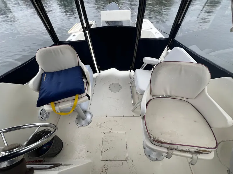 Slide: The Image of 1989 Mako 250 Cuddy Cabin interior with two white seats and a blue cushion. - 6
