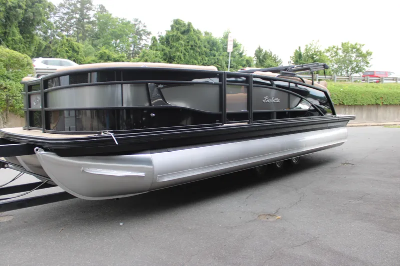 Slide: The Image of 2025 Barletta Lusso 23U pontoon boat with sleek black and silver design, parked outdoors. - 7