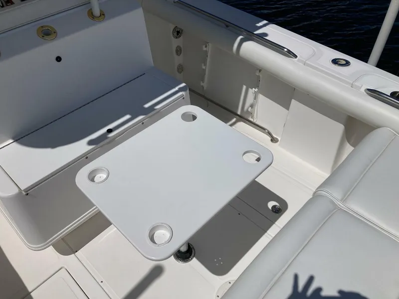 Slide: The Image of 2007 Marlago 35 boat interior with white seating and table, featuring cup holders. - 11