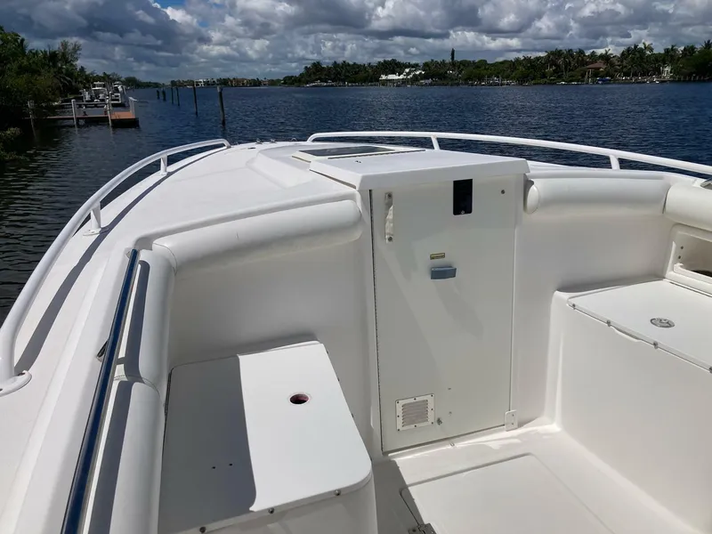 Slide: The Image of 2007 Marlago 35 boat deck with white seating, railing, and storage, on a calm waterway. - 24