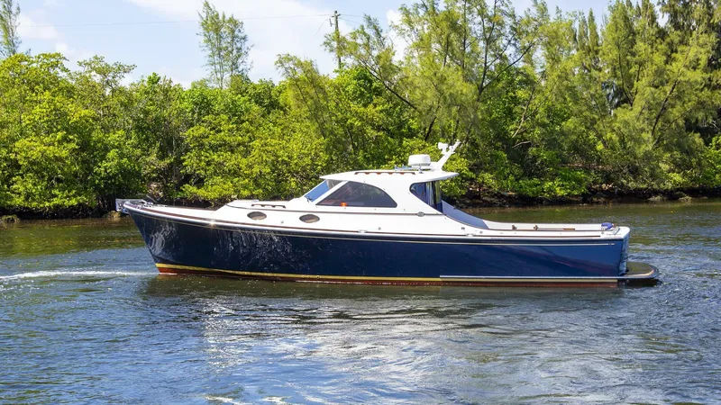 Slide: The Image of 2003 San Juan SJ 38 boat cruising on a calm river with lush greenery. - 23