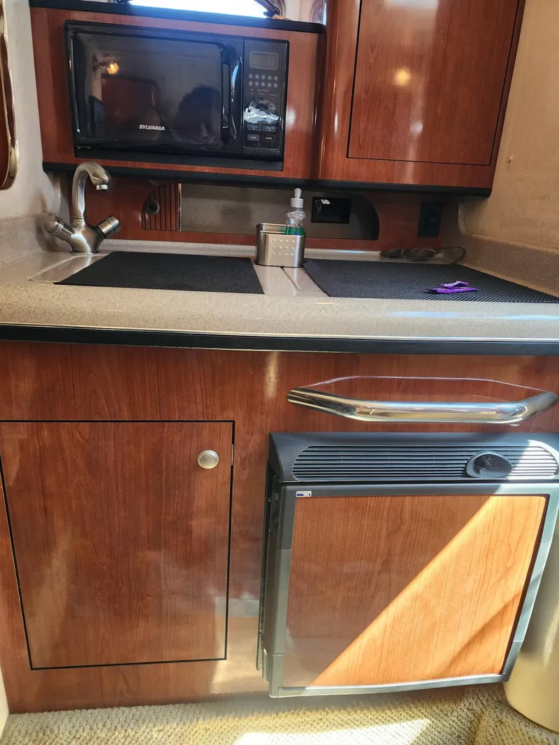 Slide: The Image of 2007 Sea Ray 280 Sundancer galley with wood cabinets, sink, microwave, and mini-fridge. - 12