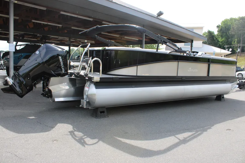 Slide: The Image of 2025 Barletta Aria 24QC pontoon boat with outboard motor, parked outdoors. - 9