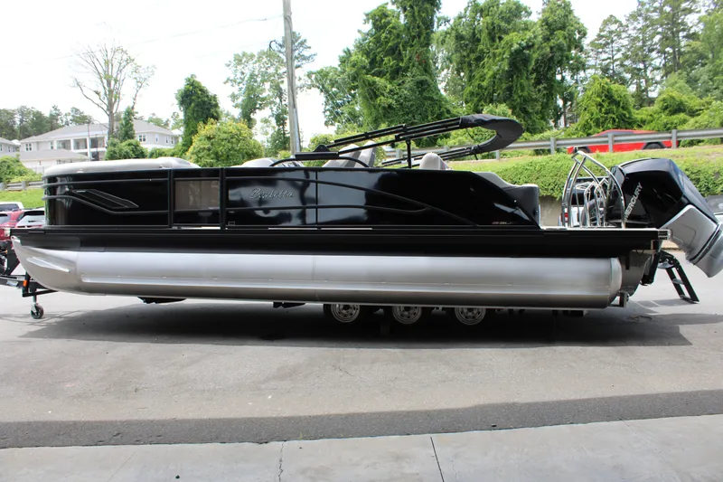 Slide: The Image of 2025 Barletta Corsa 23UC pontoon boat, sleek black design, parked outdoors. - 11
