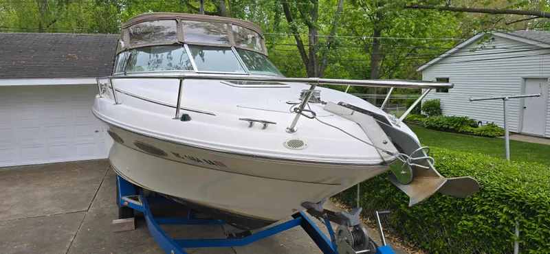 Slide: The Image of 1999 Sea Ray 280 SS boat on trailer, parked in driveway near garage and greenery. - 2