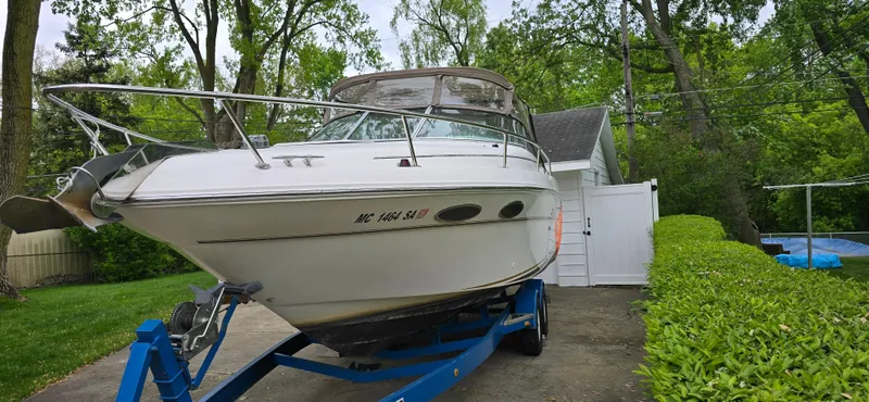 Slide: The Image of 1999 Sea Ray 280 SS boat on trailer in driveway, surrounded by greenery. - 3