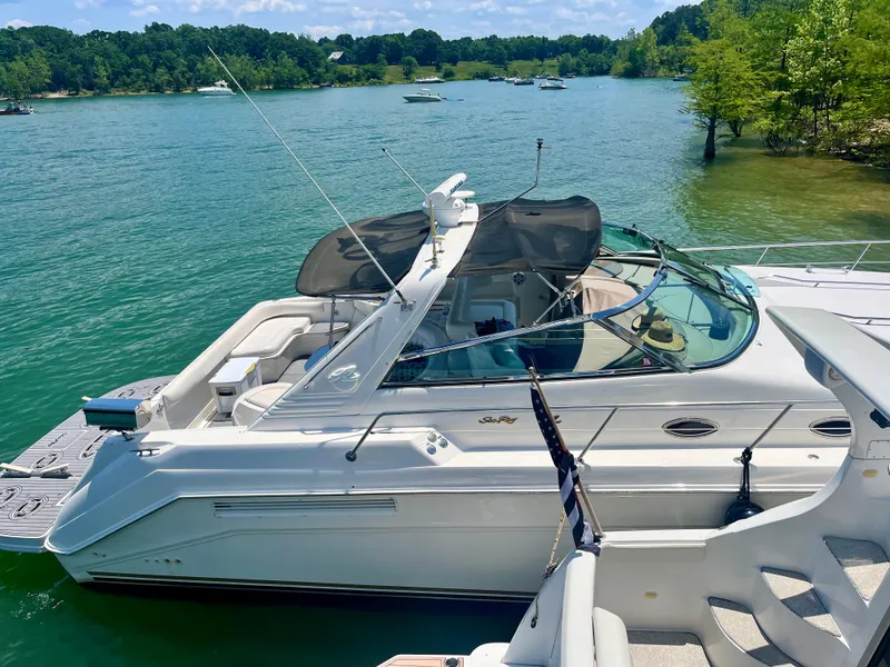 Slide: The Image of 1998 Sea Ray 500 Sundancer yacht docked on a serene lake with lush greenery. - 2