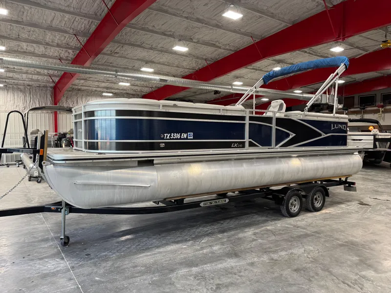 Slide: The Image of 2018 Lund LX 240 pontoon boat in a spacious indoor storage facility. - 1