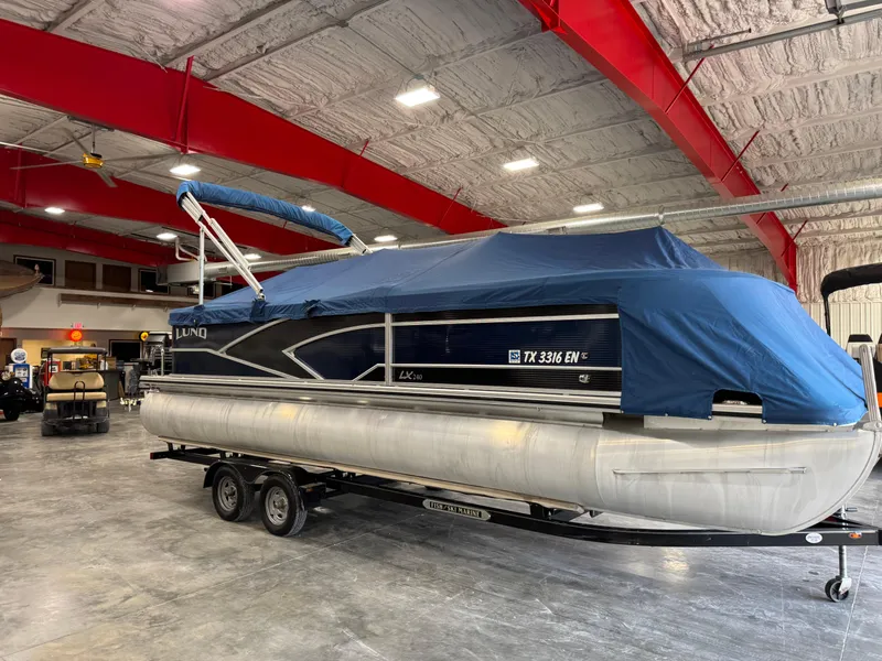 Slide: The Image of 2018 Lund LX 240 pontoon boat with blue cover in indoor storage. - 14