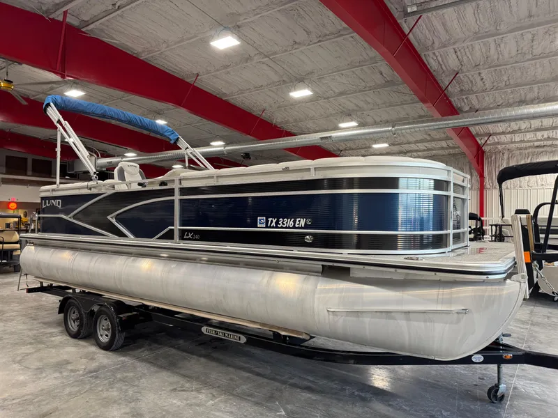 Slide: The Image of 2018 Lund LX 240 pontoon boat in a warehouse, on a trailer. - 2