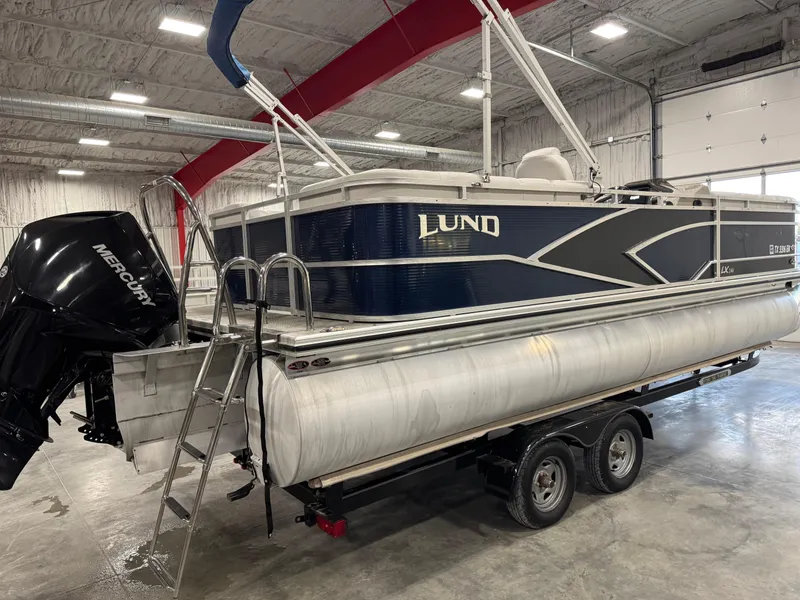 Slide: The Image of 2018 Lund LX 240 pontoon boat on trailer in indoor storage facility. - 4