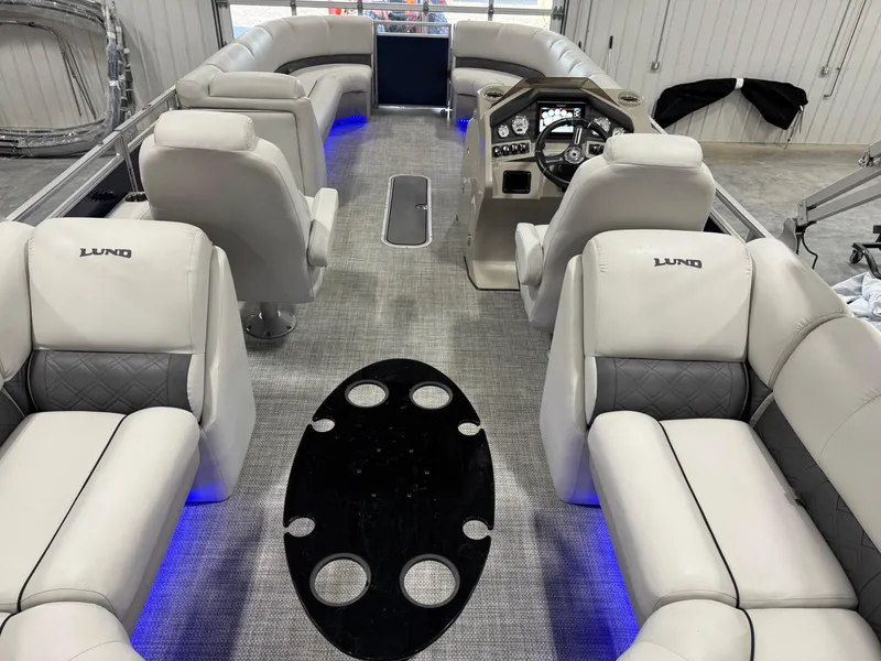 Slide: The Image of 2018 Lund LX 240 boat interior with plush seating, modern dashboard, and ambient blue lighting. - 7
