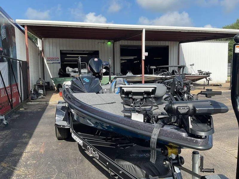 Slide: The Image of 2025 Bass Cat Eyra boat parked outside a marine service shop. - 3