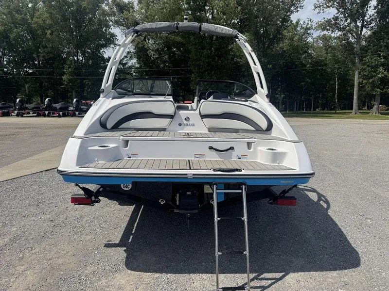 Slide: The Image of 2021 Yamaha Boats AR195, rear view with swim platform and ladder, parked outdoors. - 2
