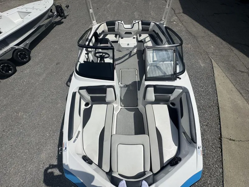 Slide: The Image of 2021 Yamaha Boats AR195 interior with seating and steering wheel, parked on pavement. - 4