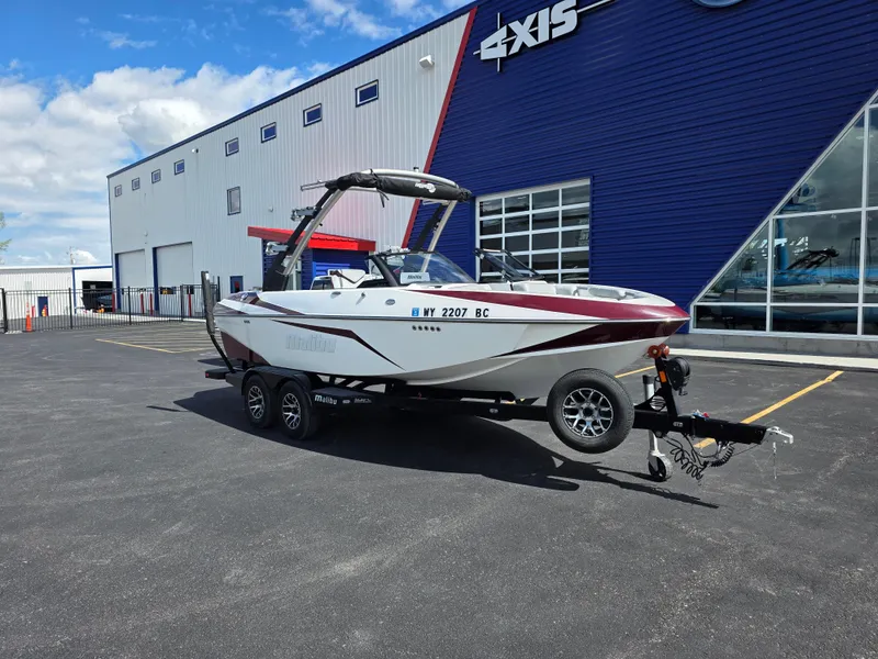 Slide: The Image of 2020 Malibu 21VLX boat on trailer outside dealership, sunny day. - 3