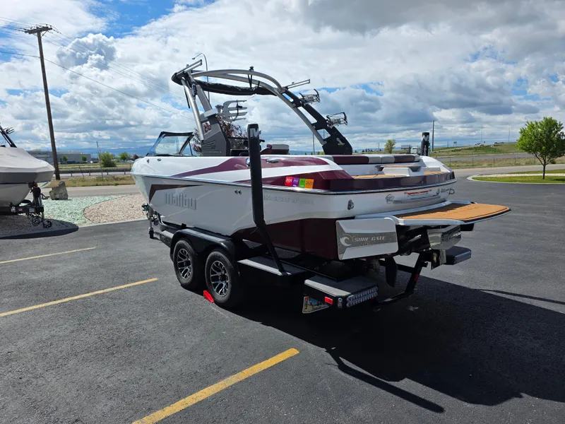 Slide: The Image of 2020 Malibu 21VLX boat on trailer in parking lot under cloudy sky. - 7