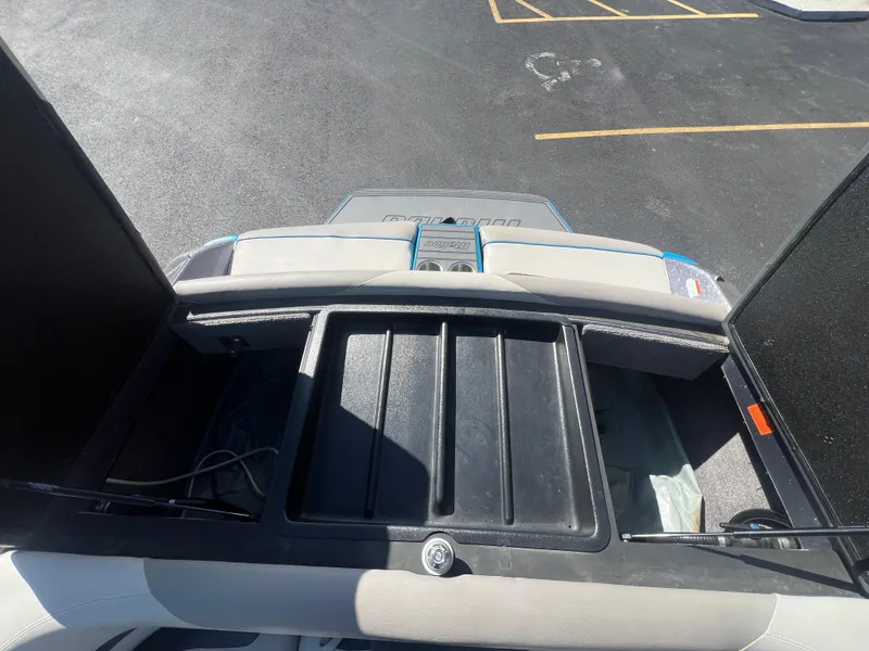 Slide: The Image of 2014 Malibu W23LSV boat storage compartment with open hatch, showing interior space. - 17