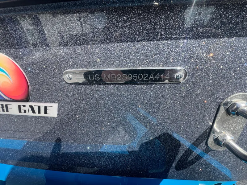 Slide: The Image of 2014 Malibu W23LSV boat with metallic finish and visible serial number plate. - 19