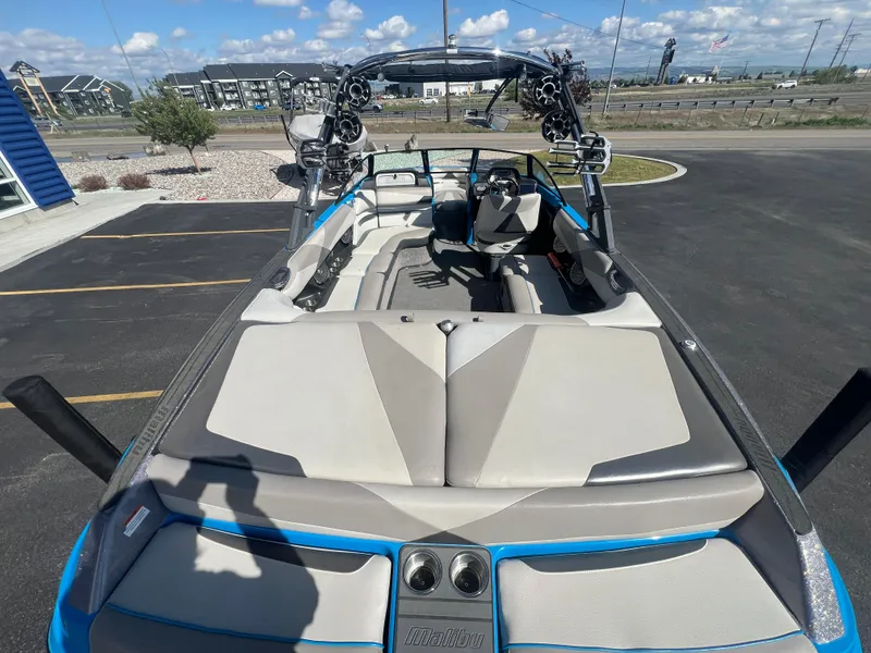 Slide: The Image of 2014 Malibu W23LSV boat with spacious seating, parked outdoors under a clear sky. - 8