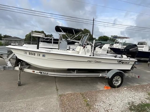 Slide: The Image of 2012 Mako Pro Skiff boat on trailer, parked outdoors under cloudy sky. - 1