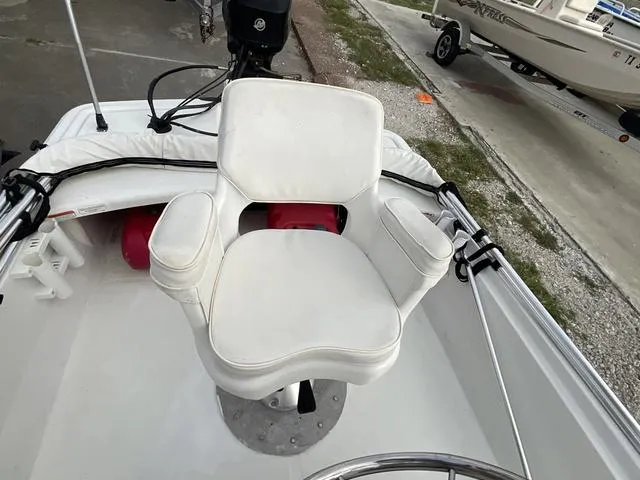 Slide: The Image of White captain's chair on 2012 Mako Pro Skiff boat, docked with visible steering wheel. - 13