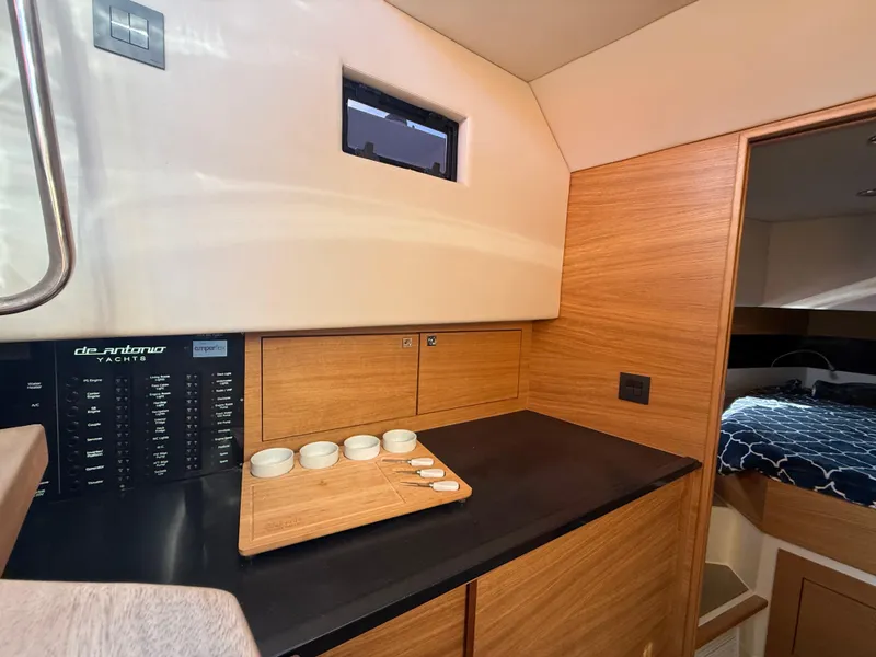 Slide: The Image of Interior of 2021 De Antonio Yachts D42, featuring a sleek wooden kitchenette and cozy cabin. - 15