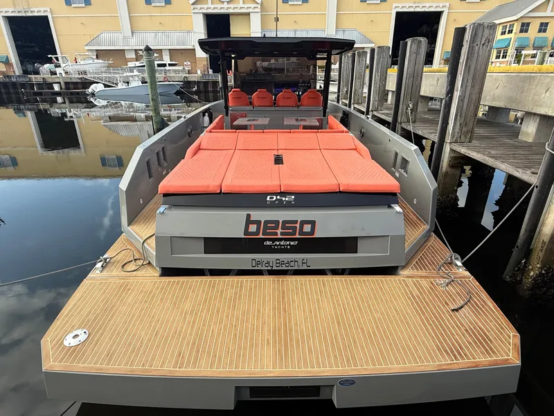 Slide: The Image of 2021 De Antonio Yachts D42 with red seating, docked at a marina. - 2