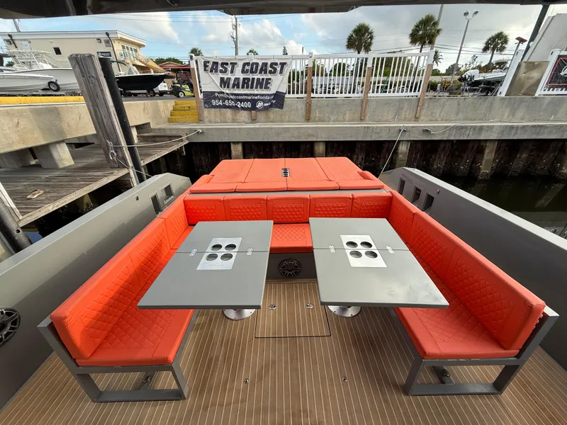 Slide: The Image of 2021 De Antonio Yachts D42 with red seating and dual tables, docked at East Coast Marine. - 4