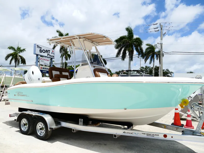 Slide: The Image of 2026 Pioneer 202 Islander boat on trailer at dealership, palm trees in background. - 1