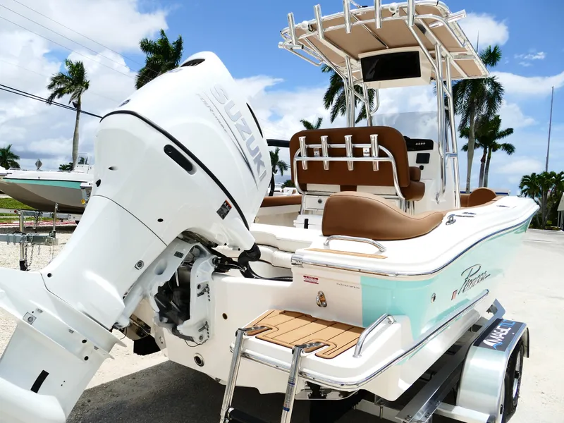 Slide: The Image of 2026 Pioneer 202 Islander boat with Suzuki engine, parked on trailer, palm trees in background. - 11