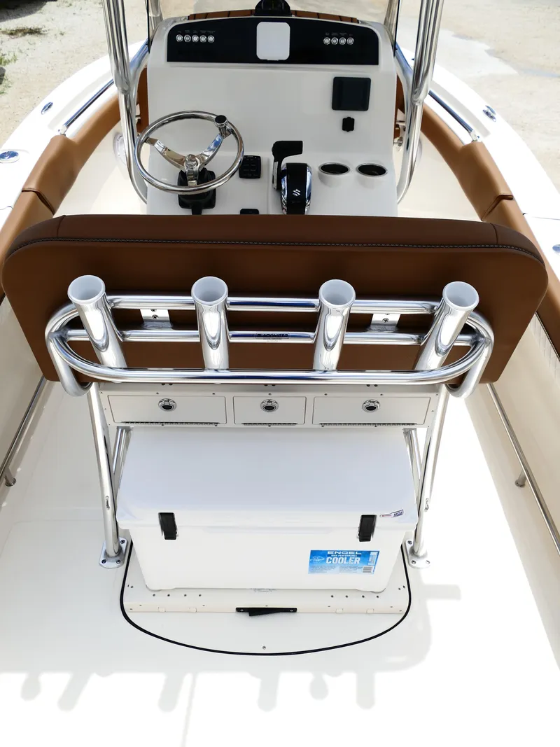 Slide: The Image of 2026 Pioneer 202 Islander boat interior with steering console, rod holders, and cooler. - 13
