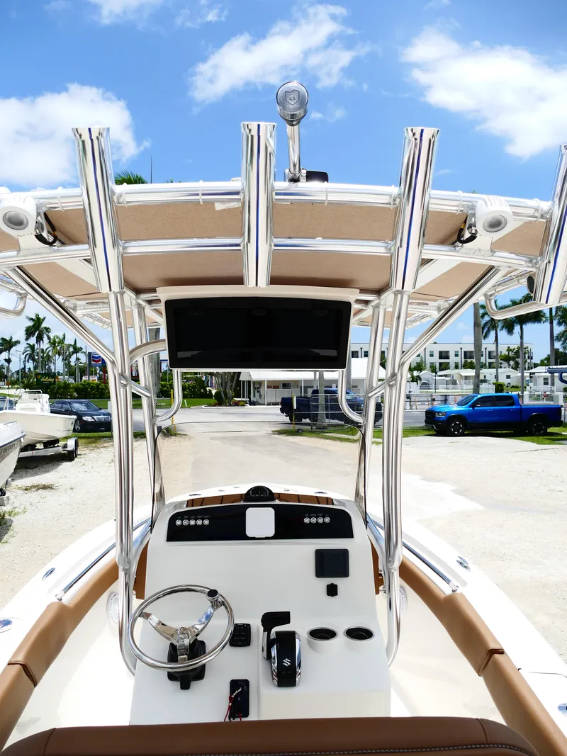 Slide: The Image of 2026 Pioneer 202 Islander boat console with steering wheel and controls, under a clear blue sky. - 15