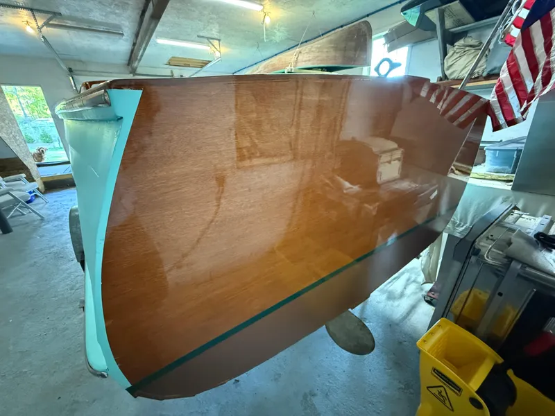 Slide: The Image of 1955 Lyman 18 Inboard boat with polished wooden hull in a garage setting. - 14