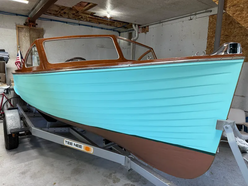 Slide: The Image of 1955 Lyman 18 Inboard boat with turquoise hull on a trailer in a garage. - 18
