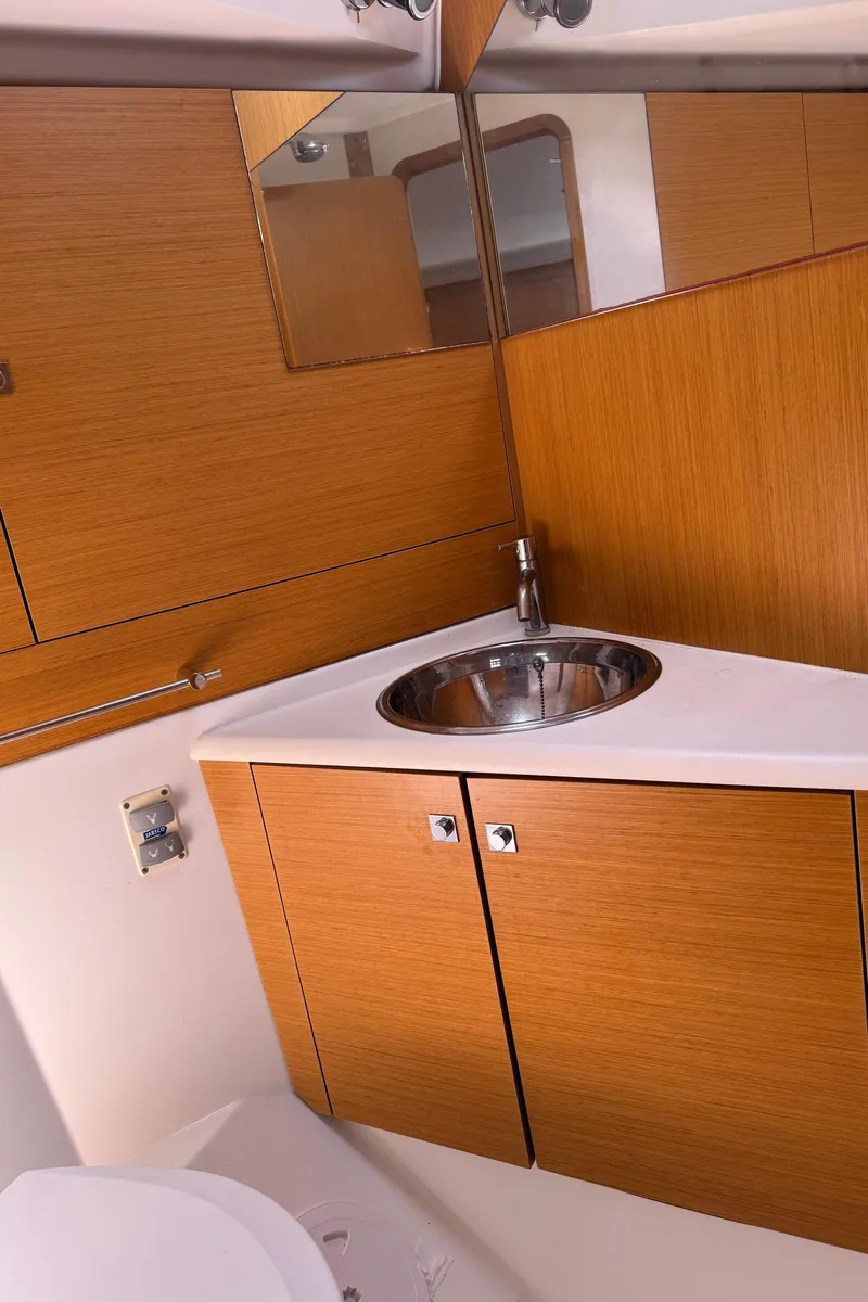 Slide: The Image of Bathroom interior of 2011 Jeanneau Sun Odyssey 45 DS yacht, featuring wooden cabinetry and stainless steel sink. - 48
