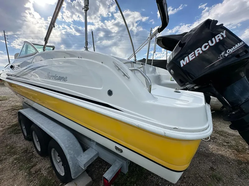 Slide: The Image of 2012 Hurricane SunDeck 237 OB boat on trailer with Mercury outboard motor, under cloudy sky. - 10