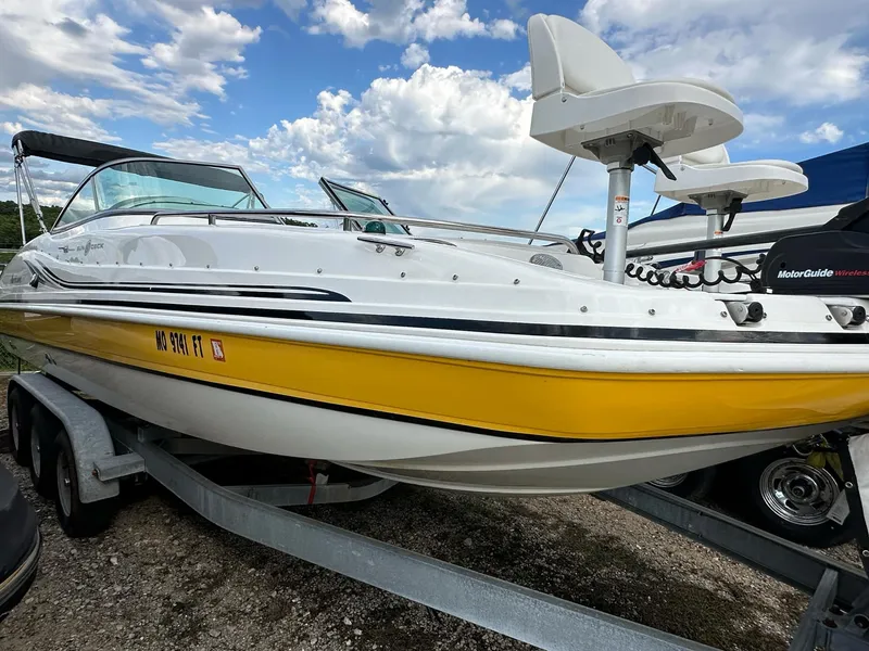 Slide: The Image of 2012 Hurricane SunDeck 237 OB boat with yellow trim on a trailer, under a cloudy sky. - 25