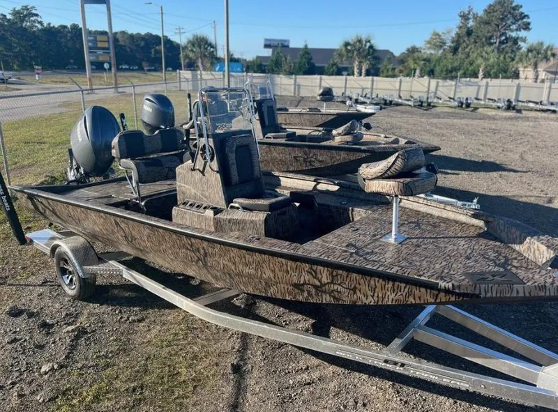 Slide: The Image of 2024 Xpress H20B boat with camouflage design on a trailer, parked outdoors. - 1