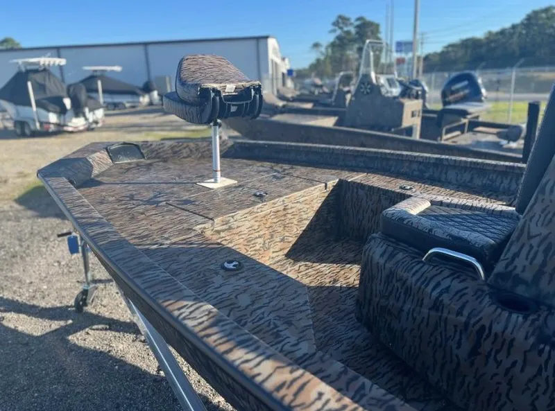 Slide: The Image of 2024 Xpress H20B boat with camouflage design, parked outdoors. - 2