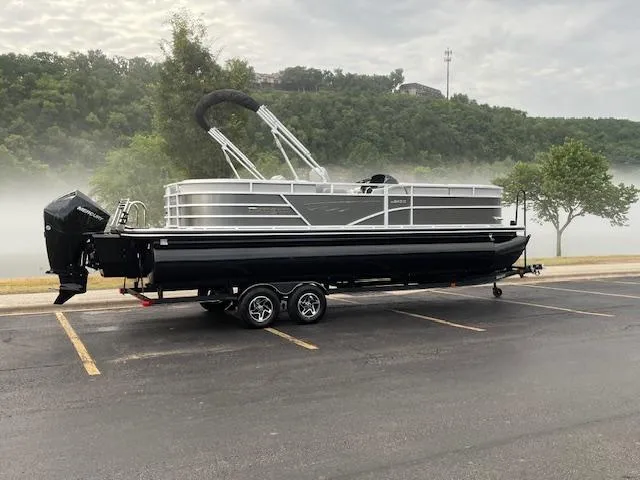 Slide: The Image of 2025 Ranger Reata 243C pontoon boat on trailer, parked in a lot. - 2