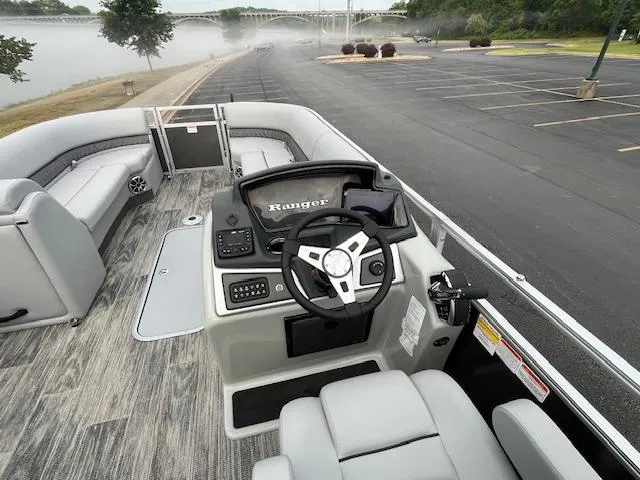 Slide: The Image of 2025 Ranger Reata 243C pontoon boat on trailer, parked in scenic outdoor setting. - 5